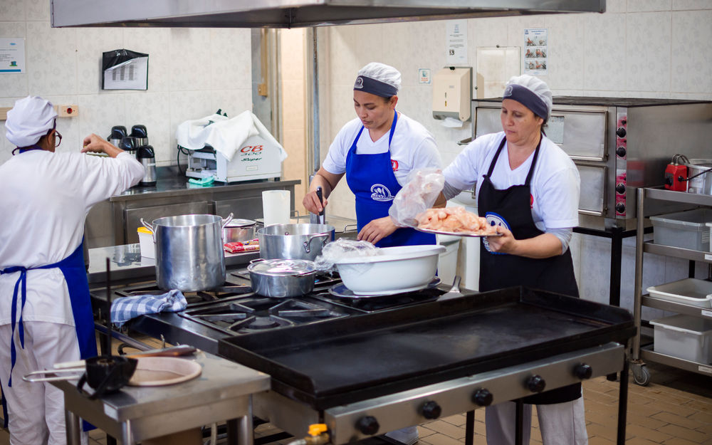 Cozinheiras da Servebem preparando refeições na cozinha industrial